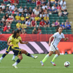 Yoreli Rincón passes the ball before Lauren Holiday closes her down.
