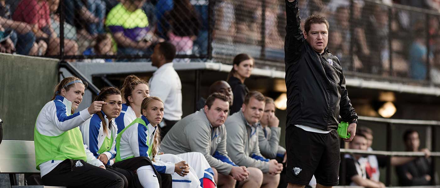 Matt Beard, head coach of the Boston Breakers, in fron of the team bench. by Mike Gridley