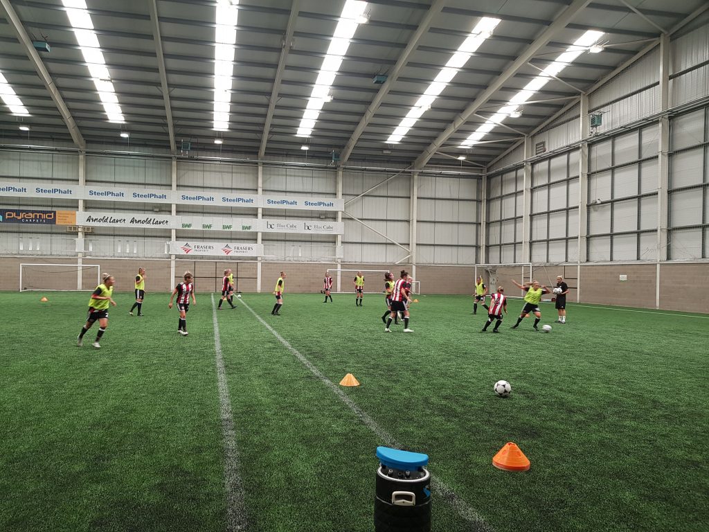 The team warms-up on the academy's full 3G indoor pitch ahead of their first match together. (Photo: Rich Laverty)