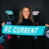 Michelle Cooper, the Kansas City Current's draft pick, holds up a Current scarf at the 2023 NWSL College Draft. (Kansas City Current Twitter)