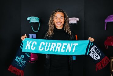 Michelle Cooper, the Kansas City Current's draft pick, holds up a Current scarf at the 2023 NWSL College Draft. (Kansas City Current Twitter)