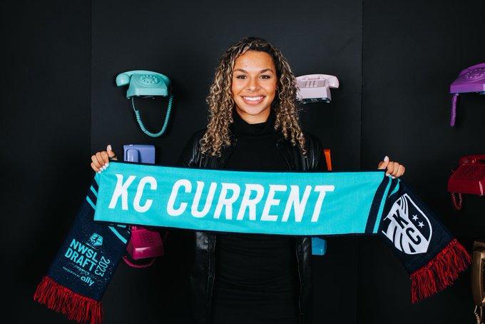 Michelle Cooper, the Kansas City Current's draft pick, holds up a Current scarf at the 2023 NWSL College Draft. (Kansas City Current Twitter)